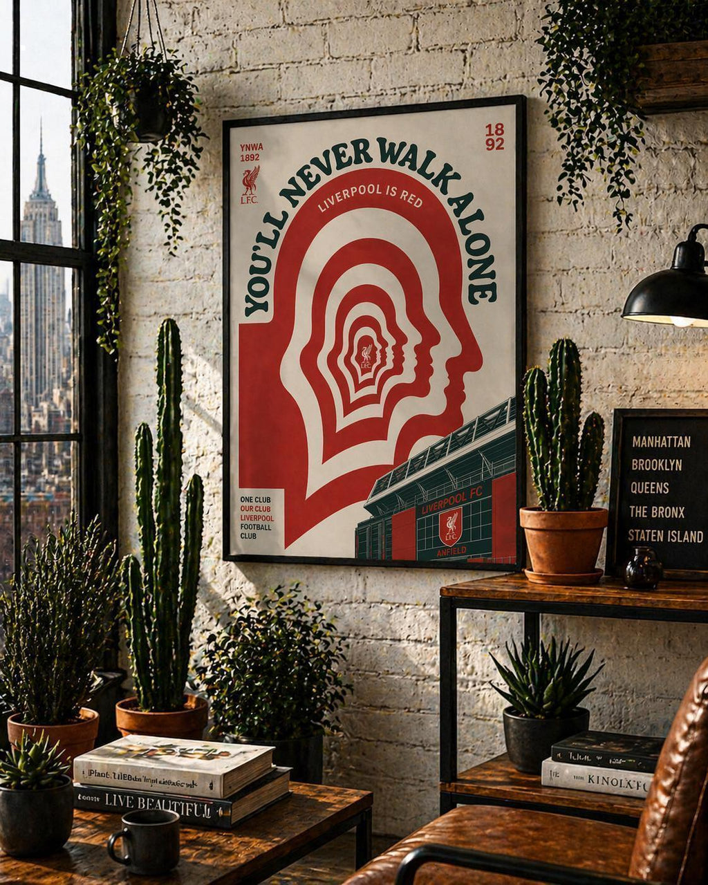May include: A framed poster with a red and white design, featuring the text "YOU'LL NEVER WALK ALONE" and "LIVERPOOL IS RED." The poster includes a head silhouette and a stadium. The image is displayed in a room with plants and a city view.